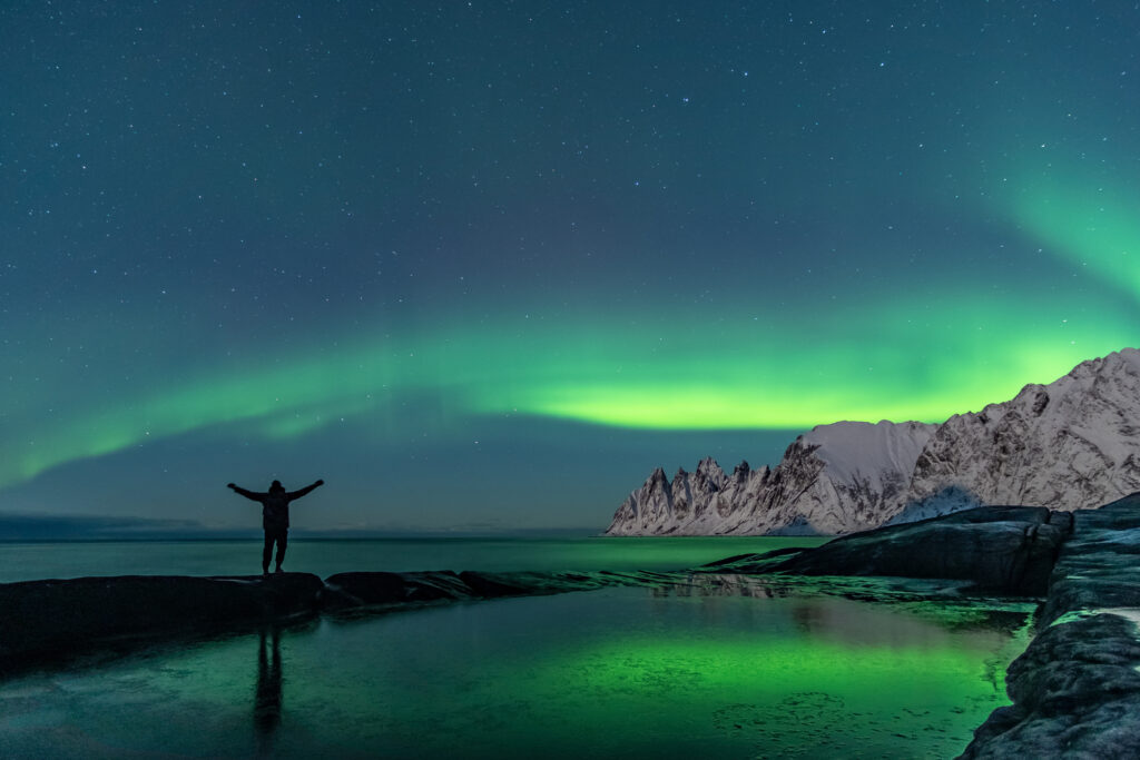 Man watching the northern lights, Aurora Borealis, Devil Teeth mountains in the background, Tungeneset, Senja, Norway Av reisegraf