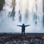 A person admirnig the beauty of Skogafoss waterfall located in Iceland Av kbarzycki