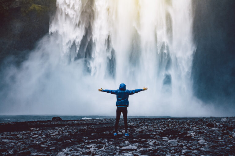 A person admirnig the beauty of Skogafoss waterfall located in Iceland Av kbarzycki
